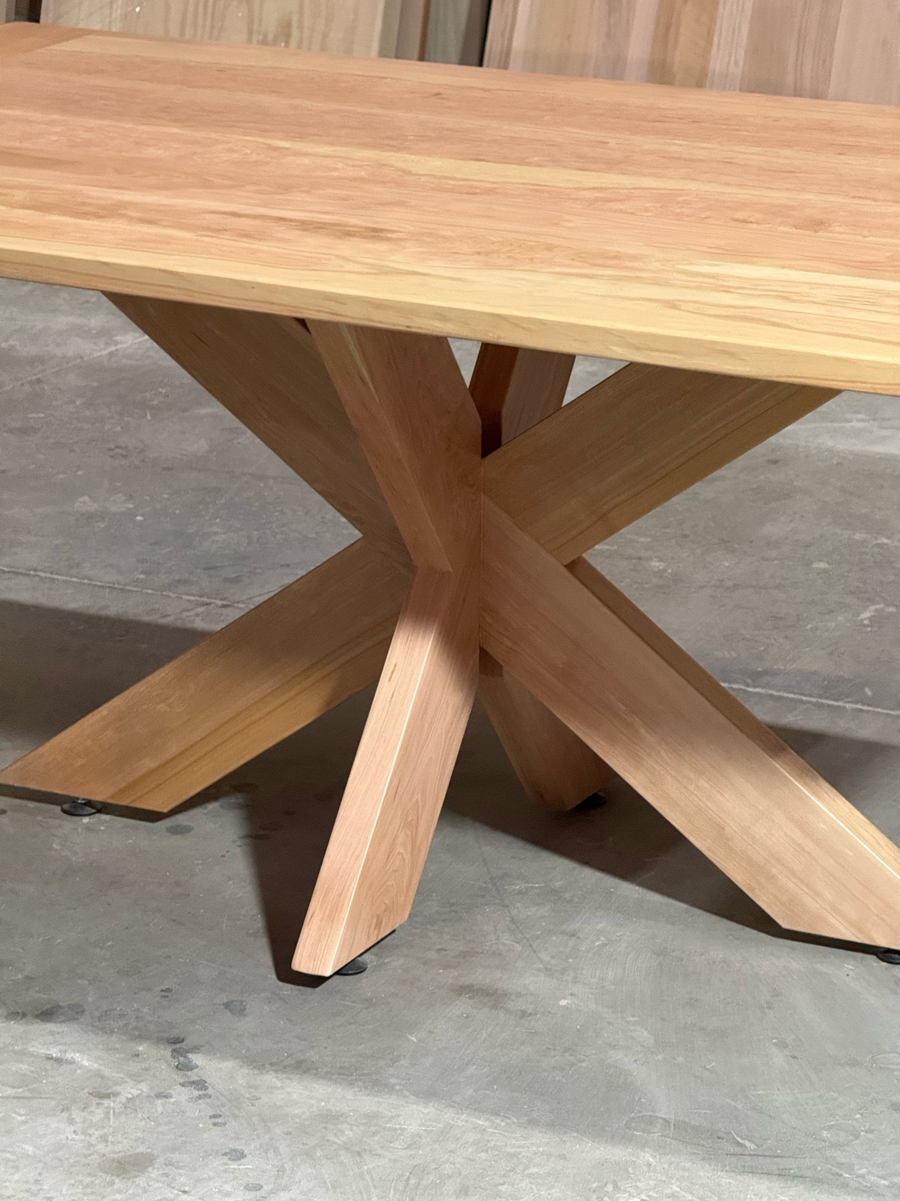Cruce de las tres patas de madera maciza en el centro de la base de la mesa de comedor rectangular Lena, en lenga natural.