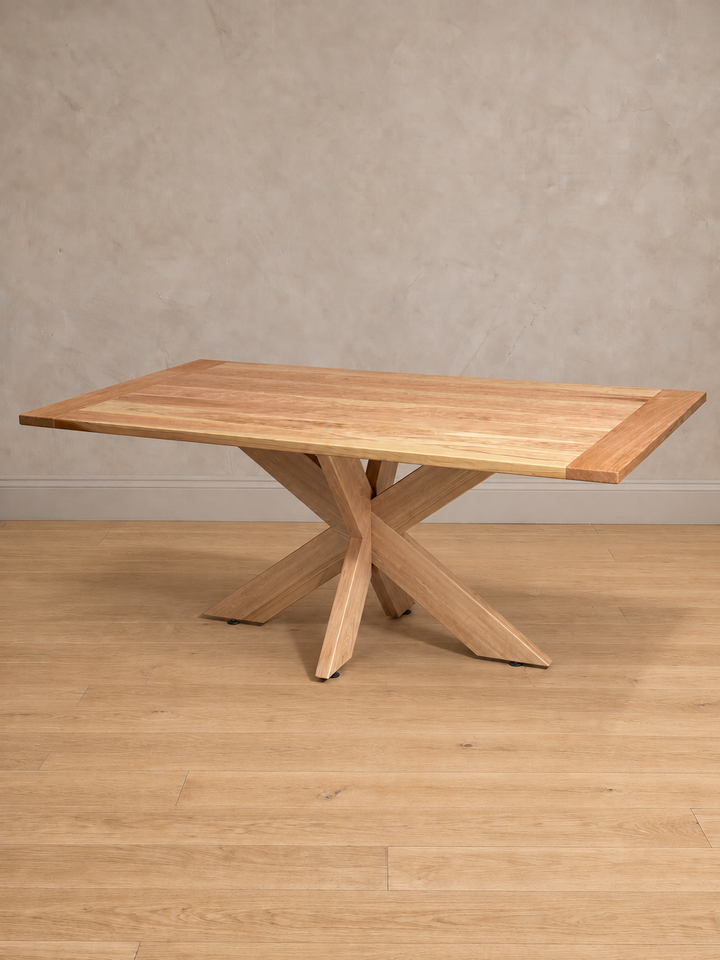 Mesa de comedor rectangular Lena en lenga natural, vista en tres cuartos, base de patas cruzadas de madera maciza.