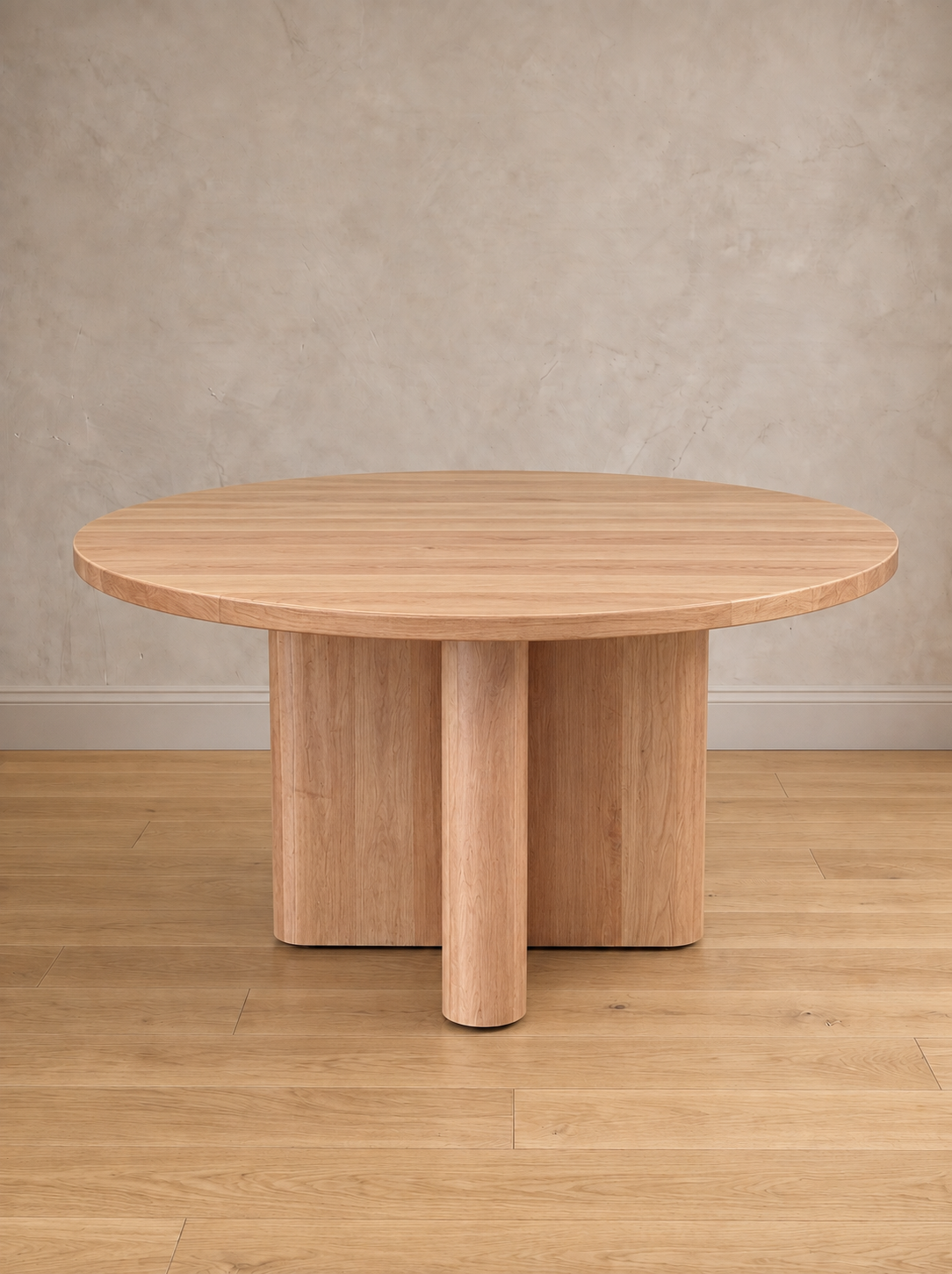 Mesa de comedor redonda Amora en lenga natural, con su base en cruz de remates curvos.