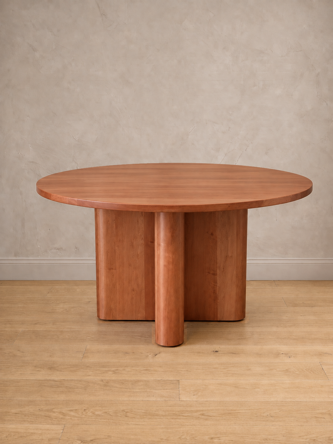 Mesa de comedor redonda Amora en roble hualle natural, con su base en cruz de remates curvos.