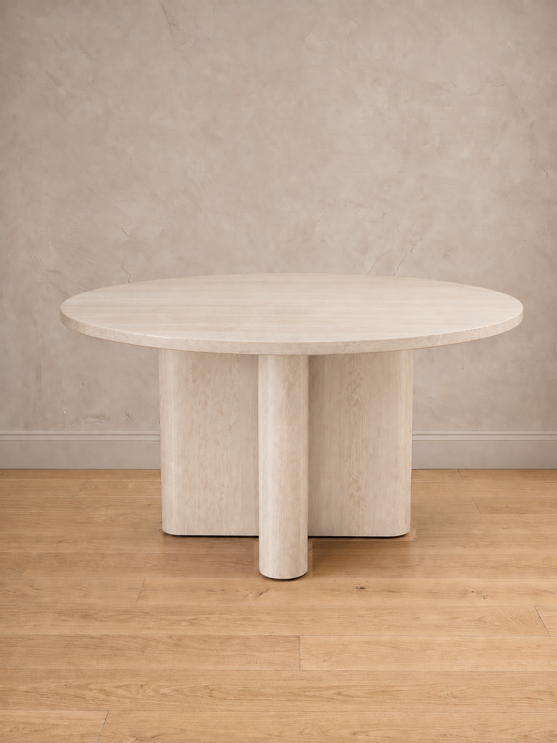 Mesa de comedor redonda Amora en tono blanco, con su base en cruz de remates curvos.