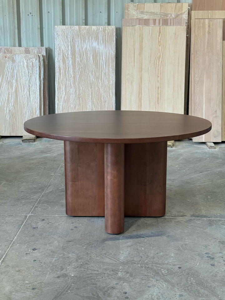 Mesa de comedor redonda Amora en lenga, vista frontal a la altura de la cubierta, base en cruz de madera maciza.