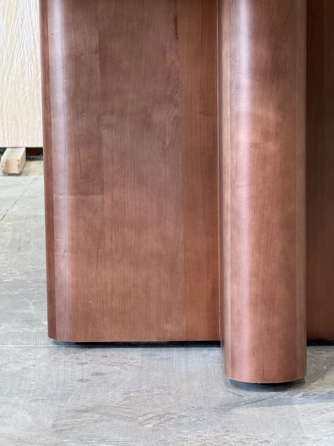 Remate curvo de la base en cruz de la mesa de comedor redonda Amora, detalle de la madera maciza.