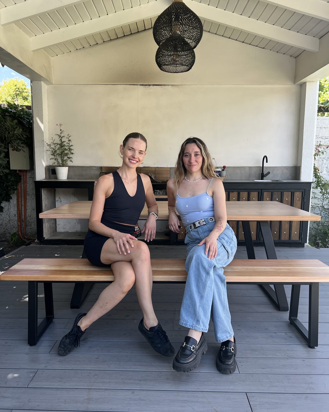 Dos clientas sentadas en una mesa con bancas de lenga en una terraza